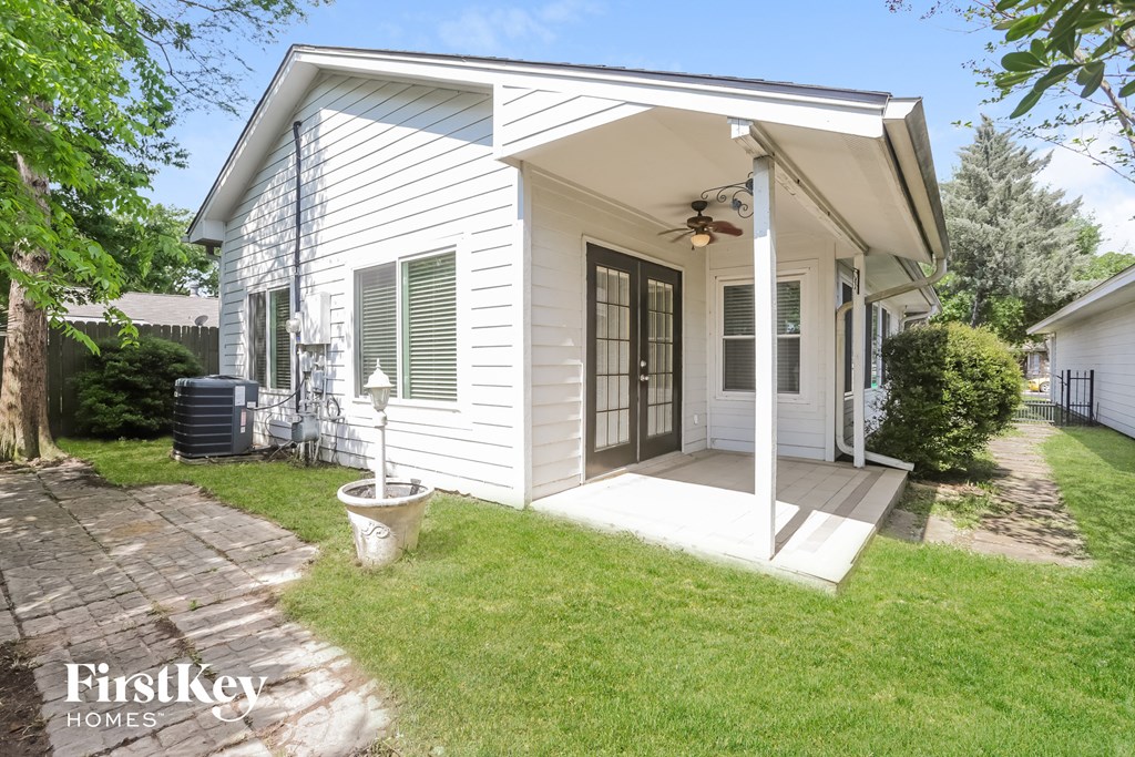 a small white house with a porch and a backyard with grass and a patio