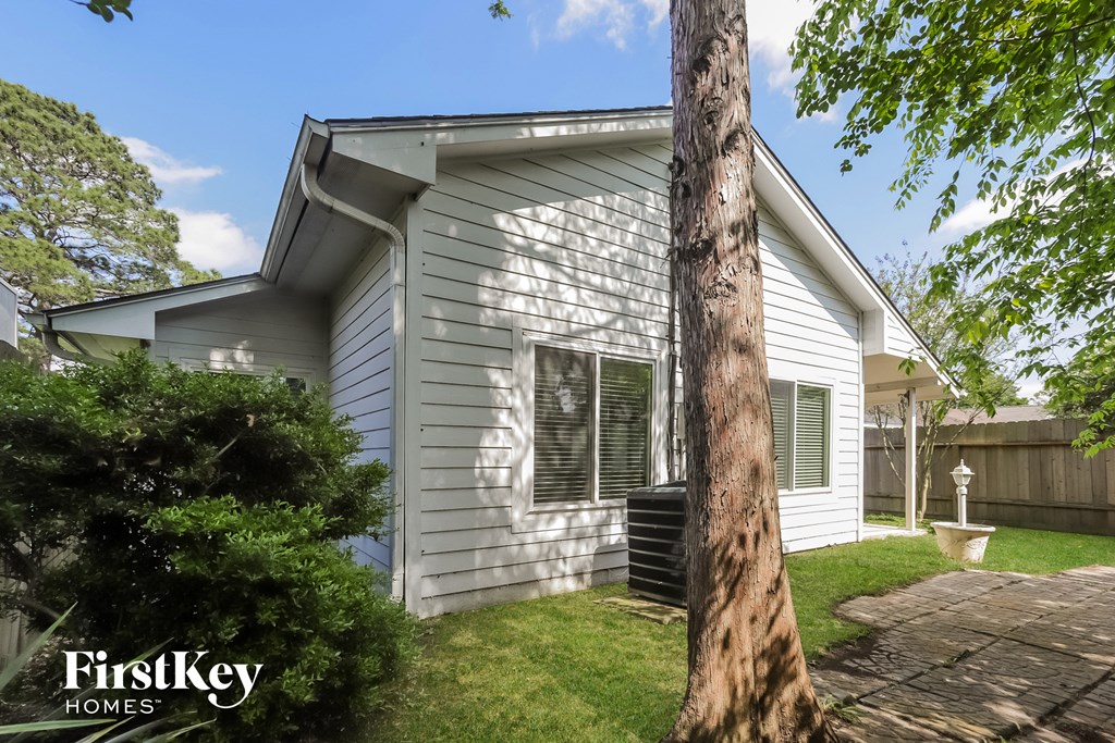 the exterior of a white house with a tree in the yard