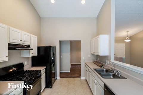 a kitchen with white cabinets and a black stove and a sink