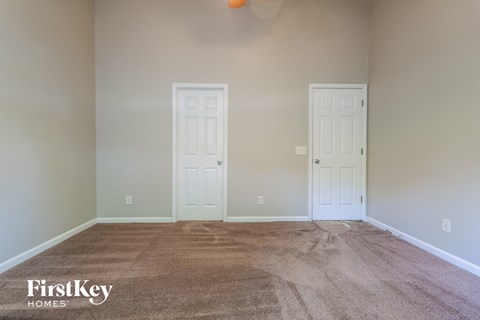 a living room with carpet and two doors