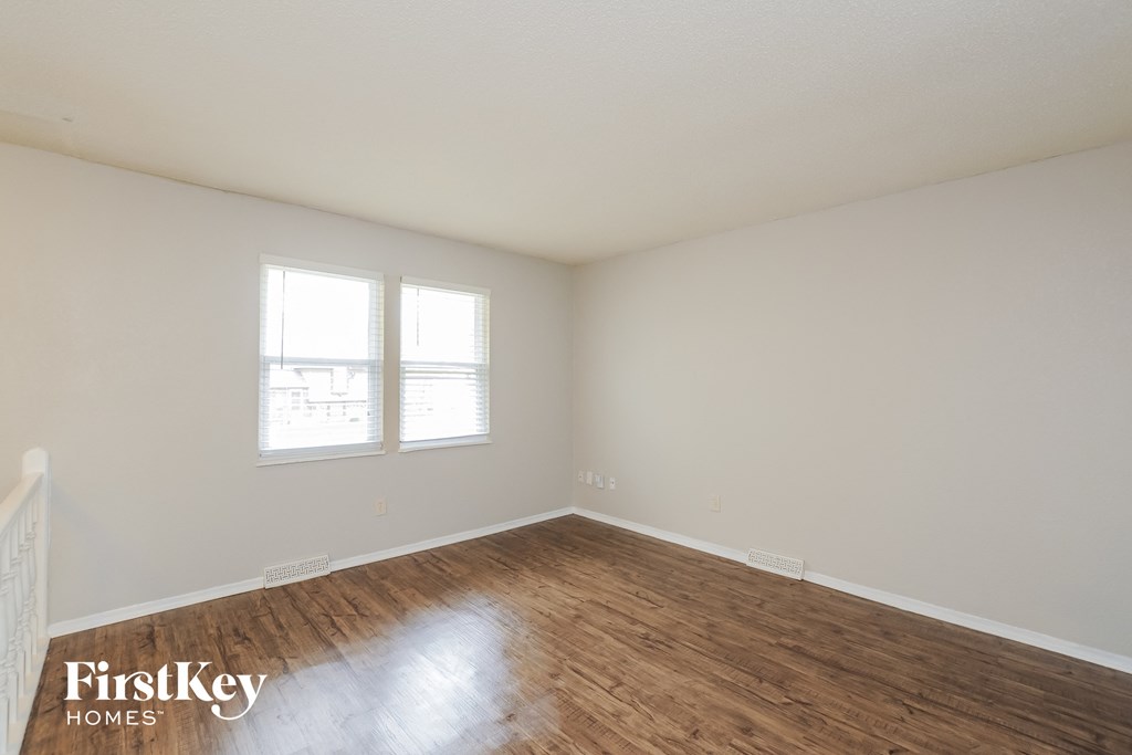 A room with wooden floors and two windows.