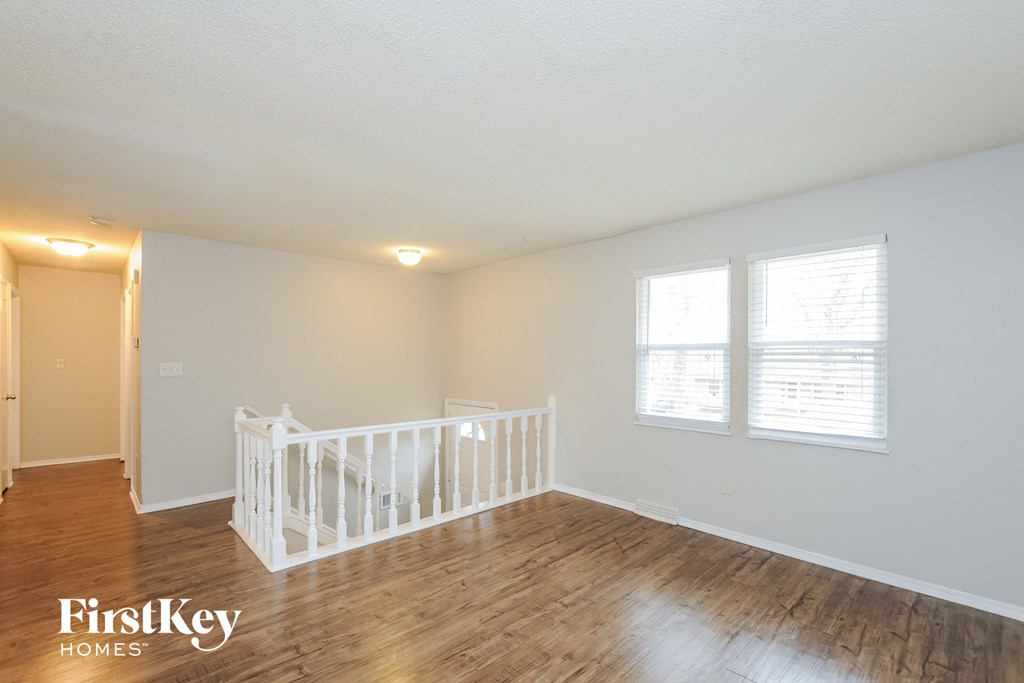 A white crib sits in a room with wooden floors and white walls.
