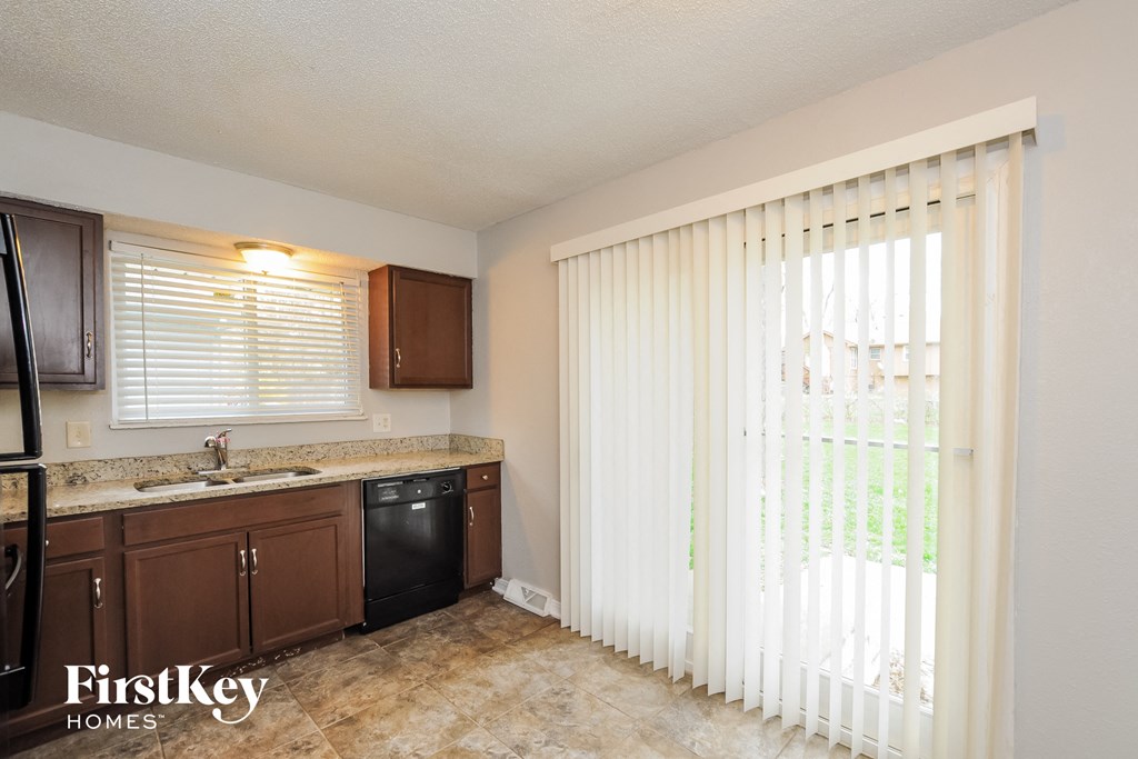 A kitchen with brown cabinets and a black dishwasher.