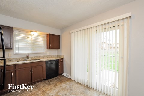 A kitchen with brown cabinets and a black dishwasher.