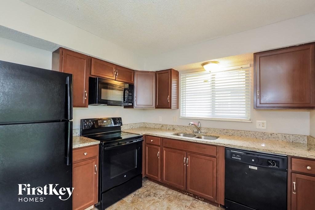 A kitchen with brown cabinets and black appliances.