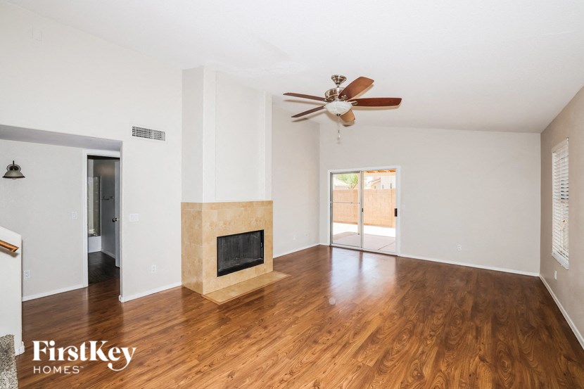 A spacious living room with a fireplace and a ceiling fan.