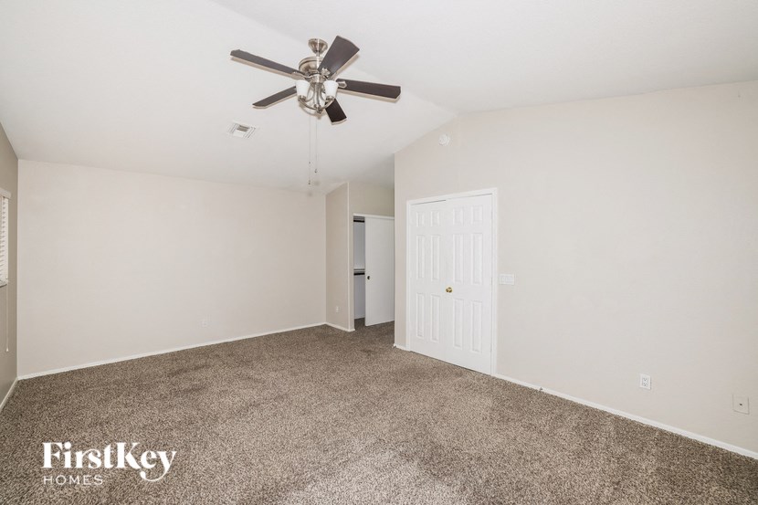 A spacious room with a ceiling fan and two doors.