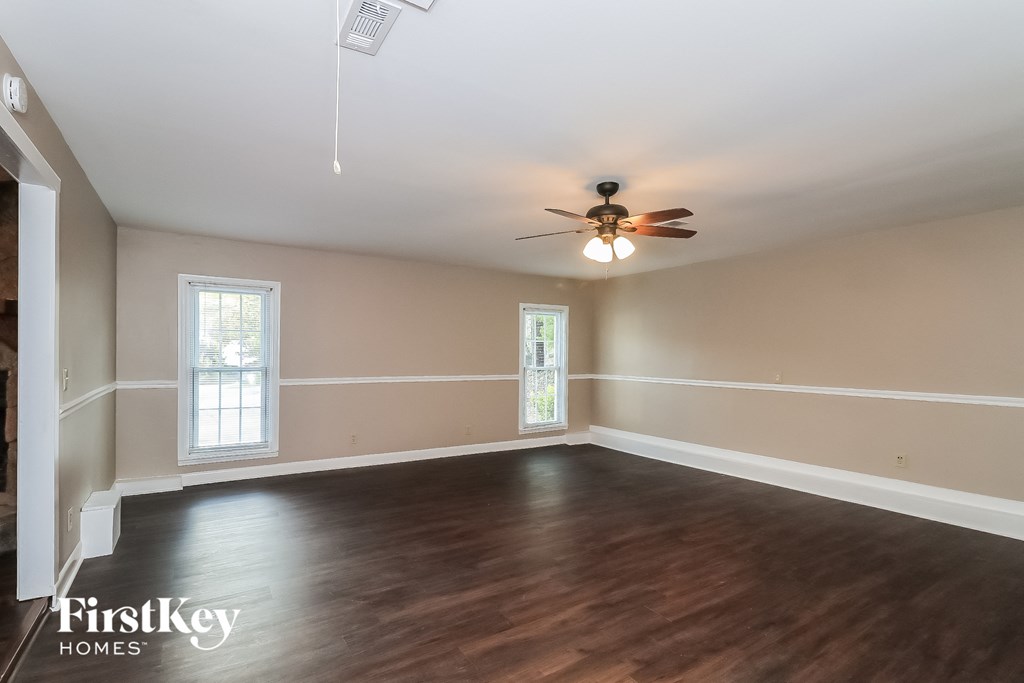 an empty living room with wood floors and a ceiling fan