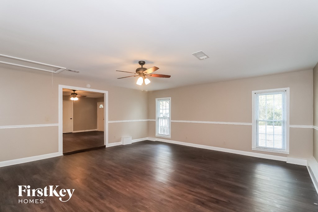 an empty living room with wood floors and a ceiling fan
