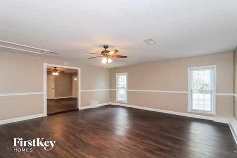 an empty living room with wood floors and a ceiling fan