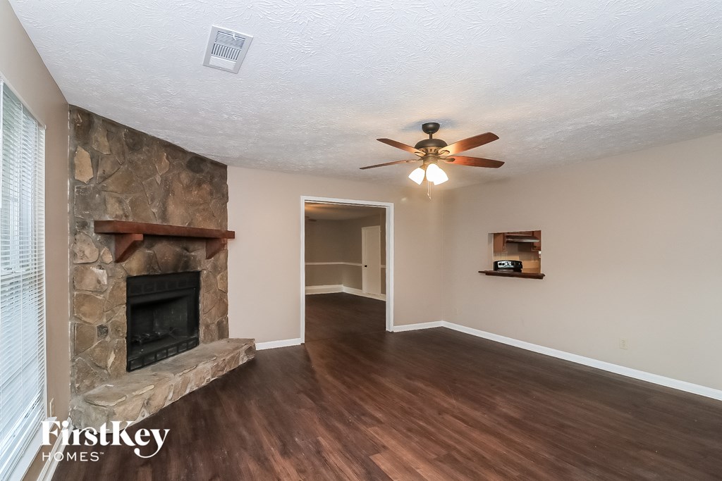 a living room with a stone fireplace and a ceiling fan