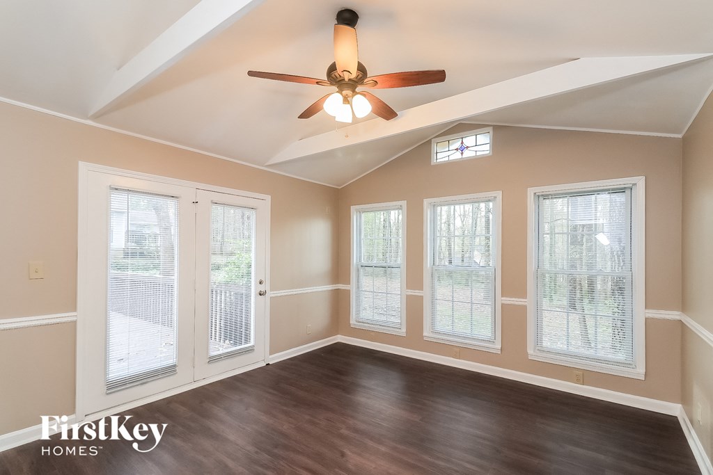 an empty living room with a ceiling fan and windows