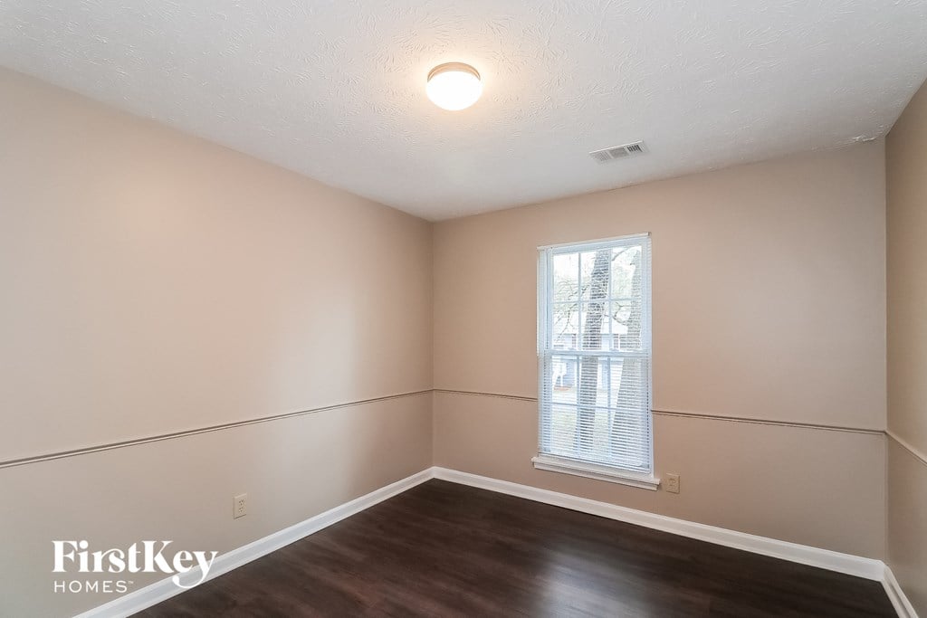 the living room of an empty house with wood flooring and a window