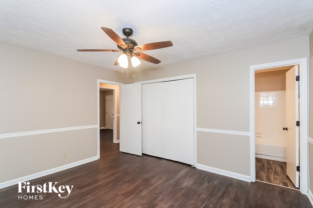 a living room with a ceiling fan and a door to a closet