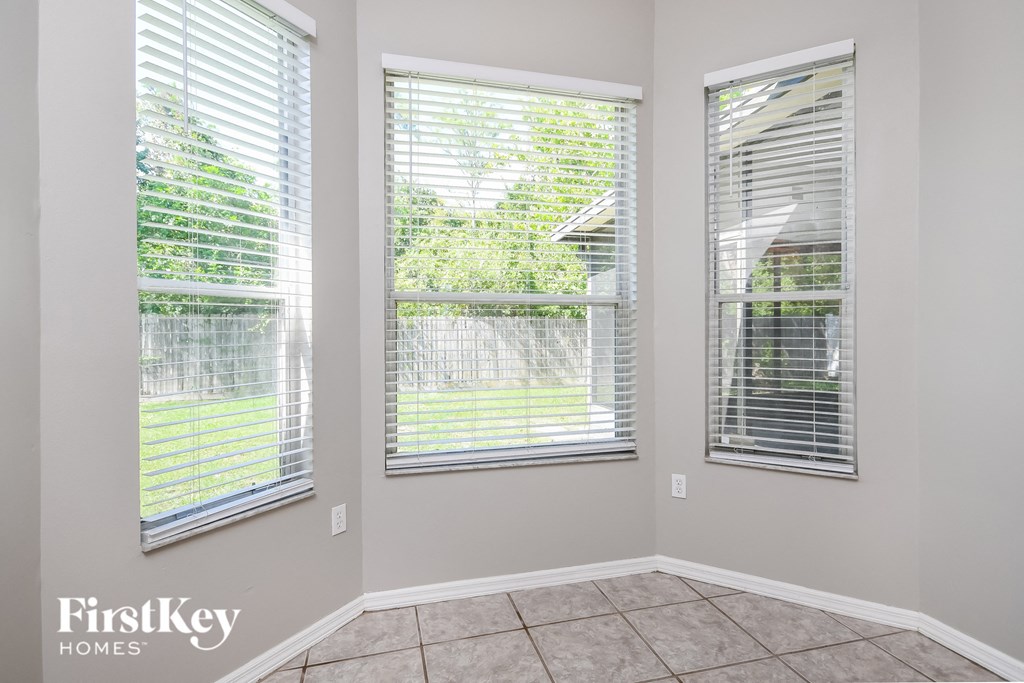 a living room with three windows and a tile floor