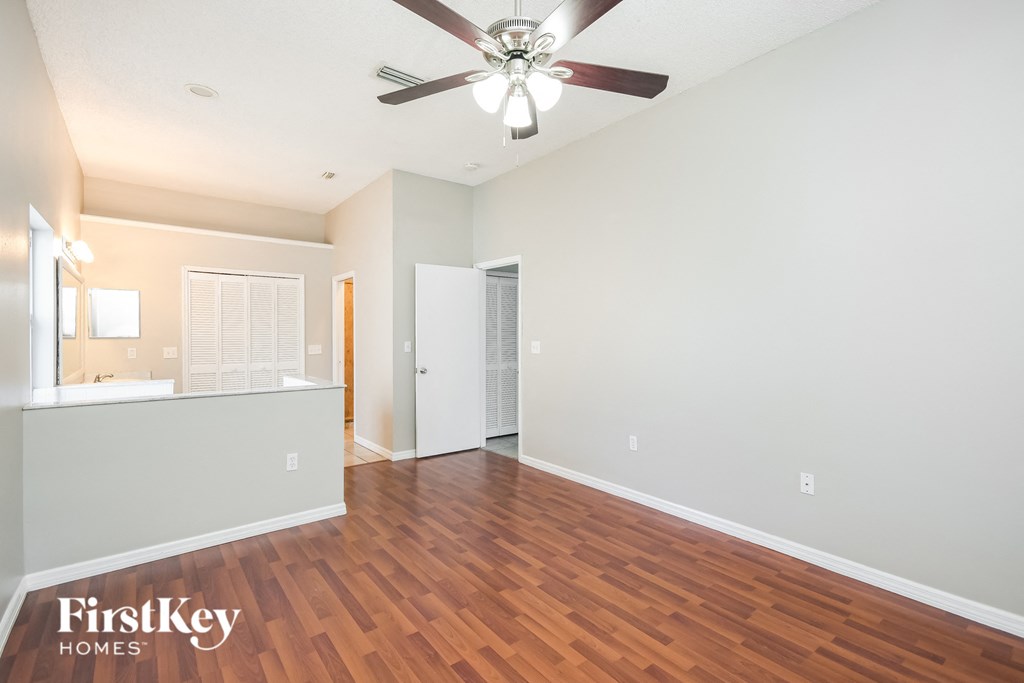 an empty living room with wood flooring and a ceiling fan