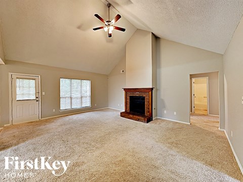 an empty living room with a fireplace and a ceiling fan