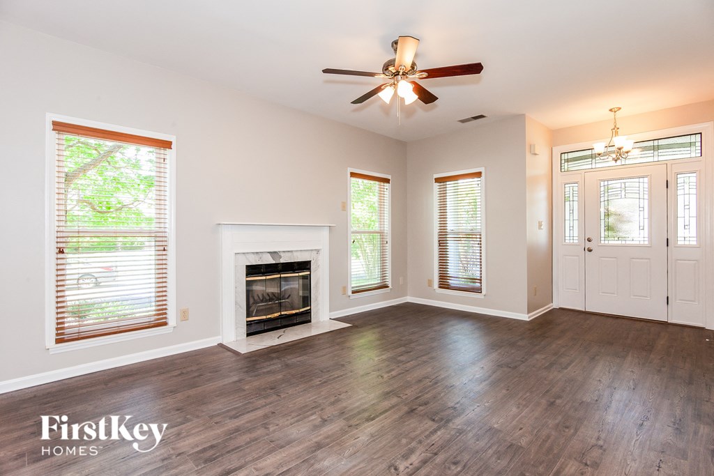 an empty living room with a fireplace and a ceiling fan