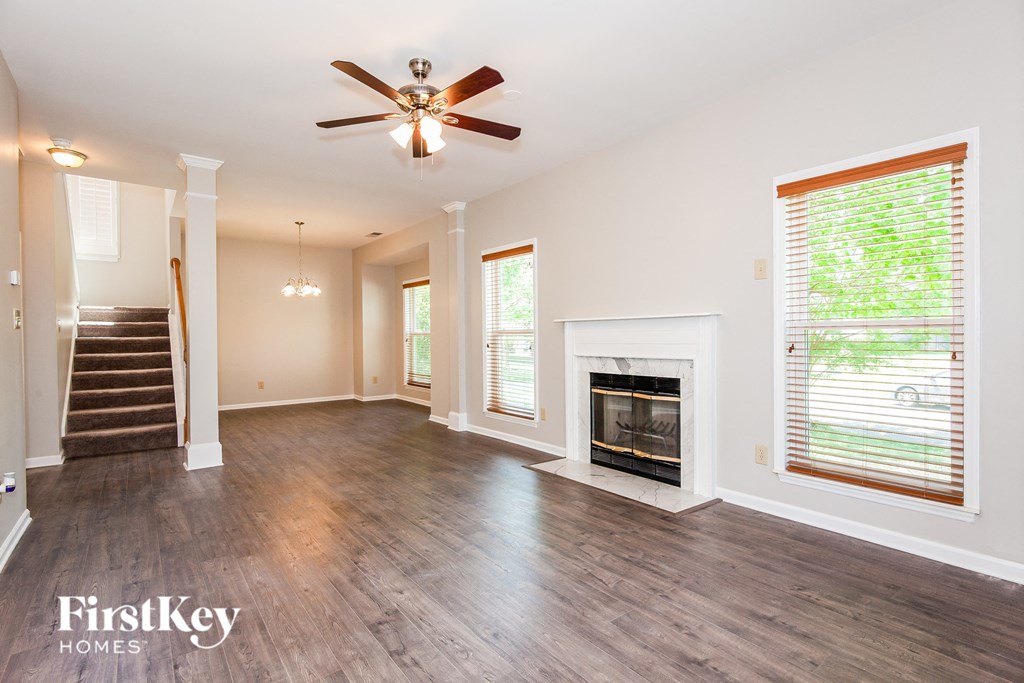 an empty living room with a fireplace and a ceiling fan