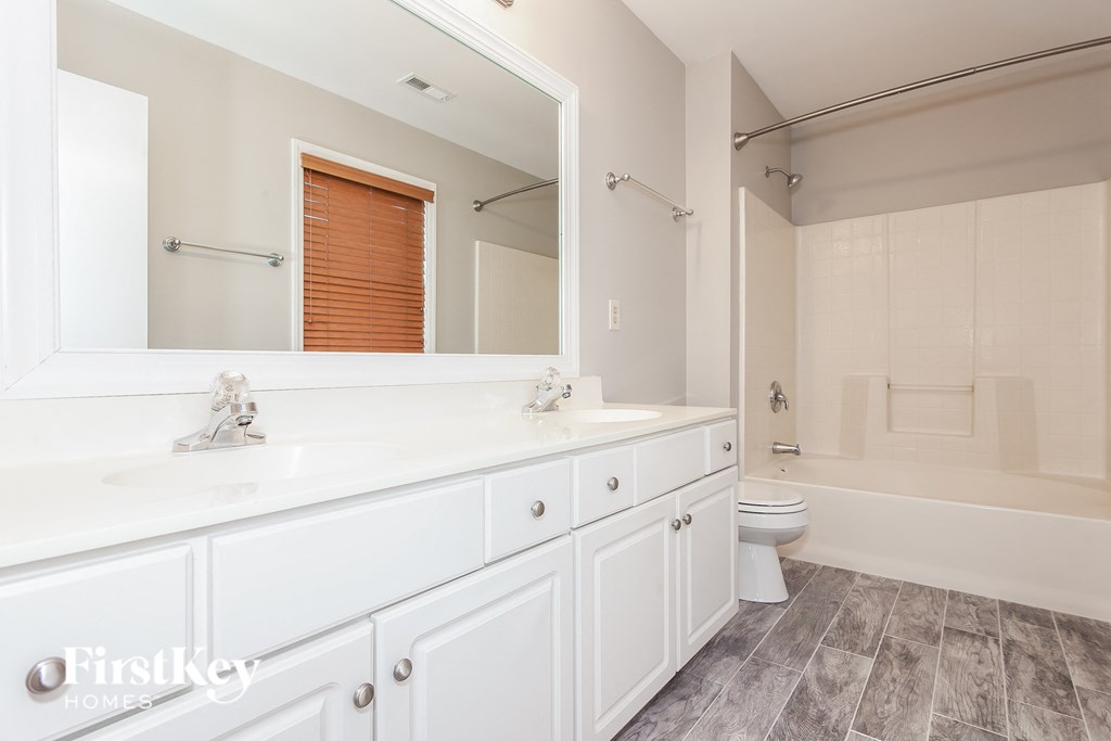 a bathroom with two sinks and a toilet and a large mirror