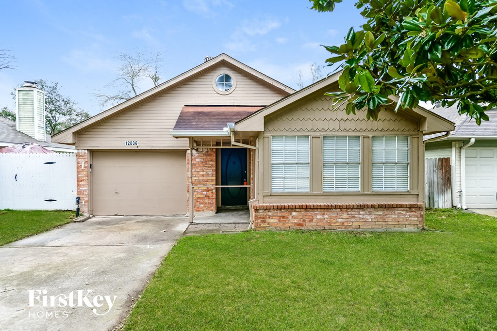 a small tan house with a driveway and a garage door