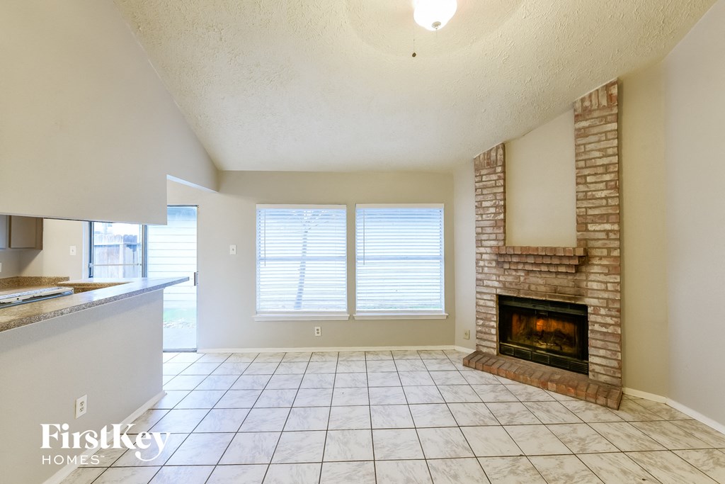 an empty living room with a fireplace and a kitchen