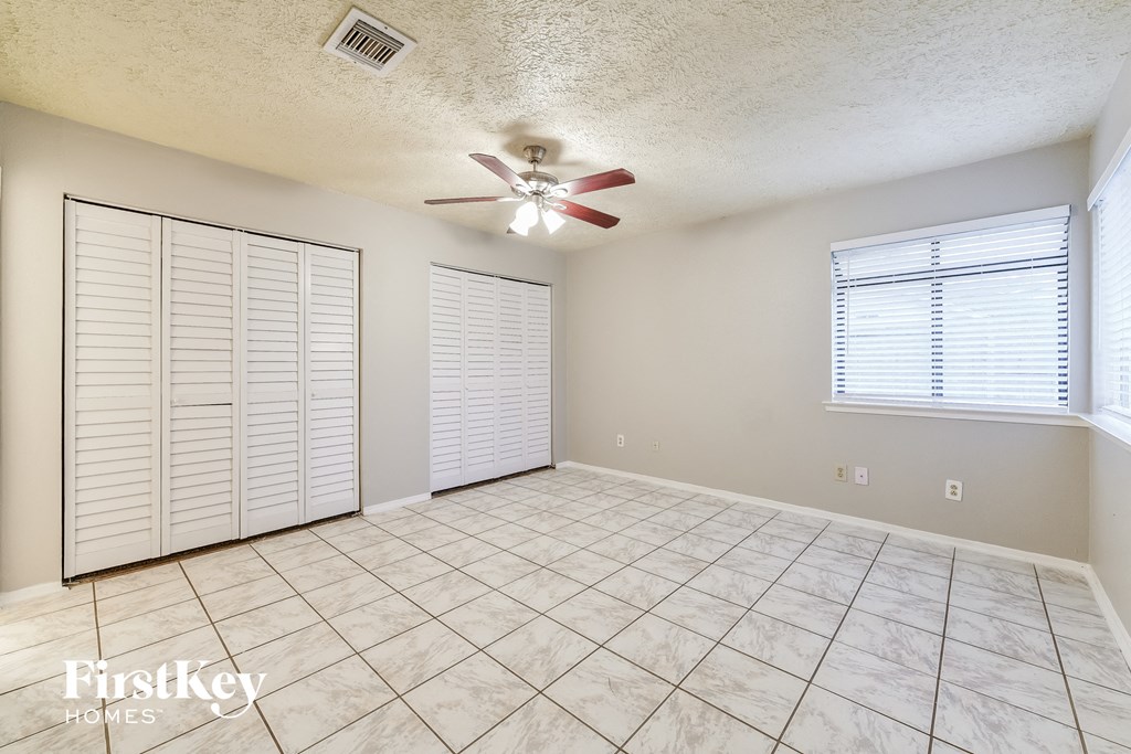 an empty living room with a ceiling fan and a tile floor
