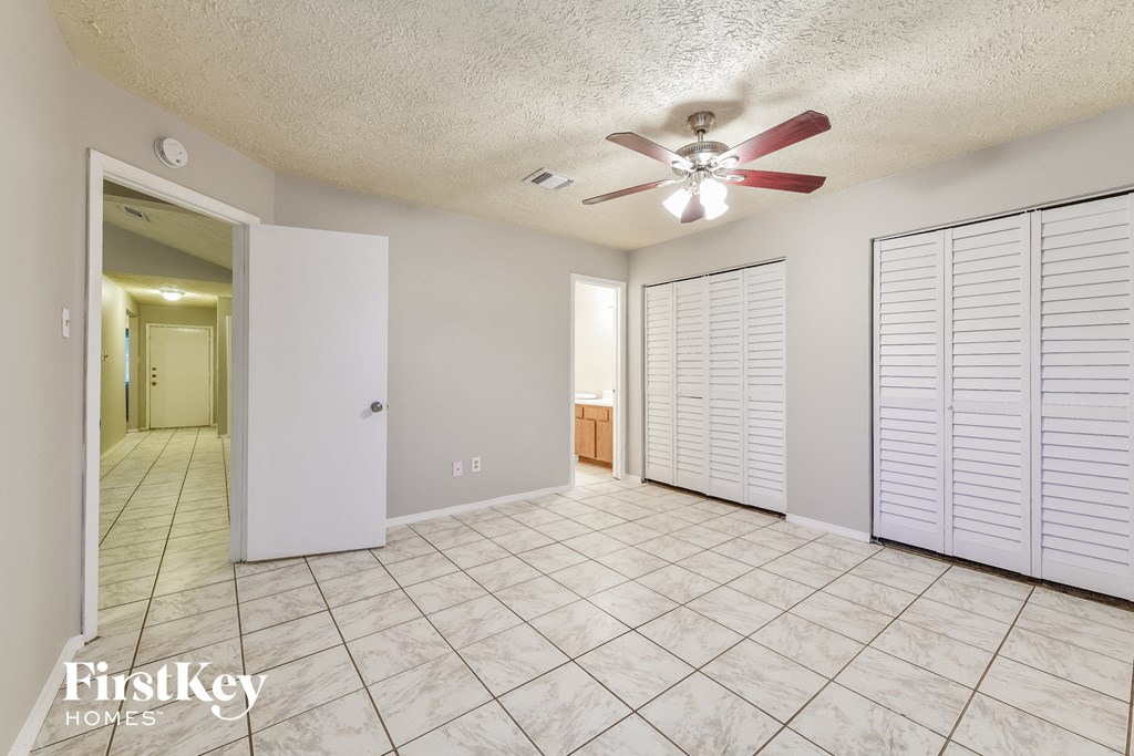 an empty living room with a ceiling fan and tile flooring