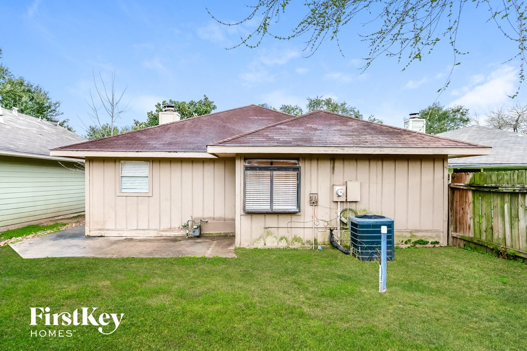 a beige house with a blue hose in the yard