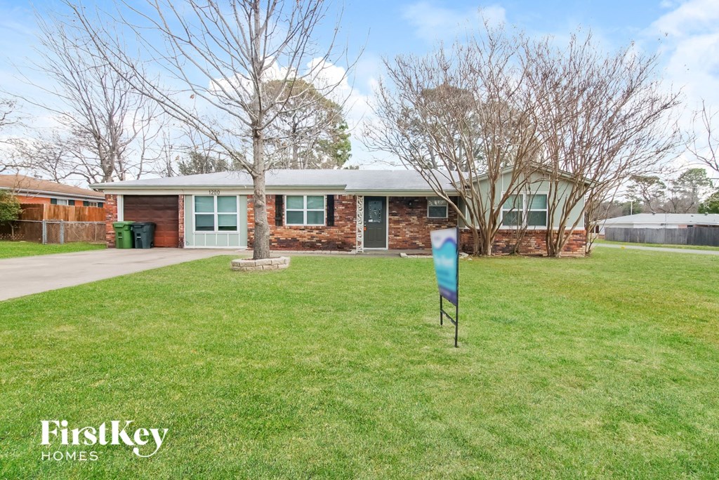 a brick house with a yard and a blue sign in the grass