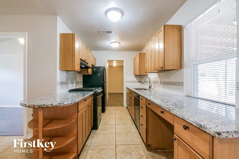 a kitchen with wood cabinets and granite counter tops and a black refrigerator