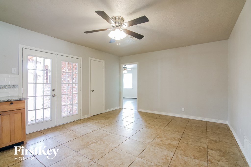 an empty living room with a ceiling fan and tiled floor