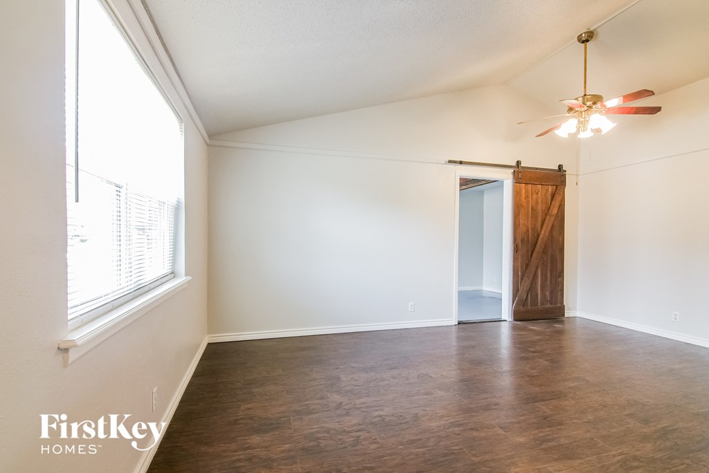 an empty living room with a large window and a ceiling fan