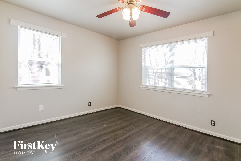 a bedroom with wood floors and a ceiling fan