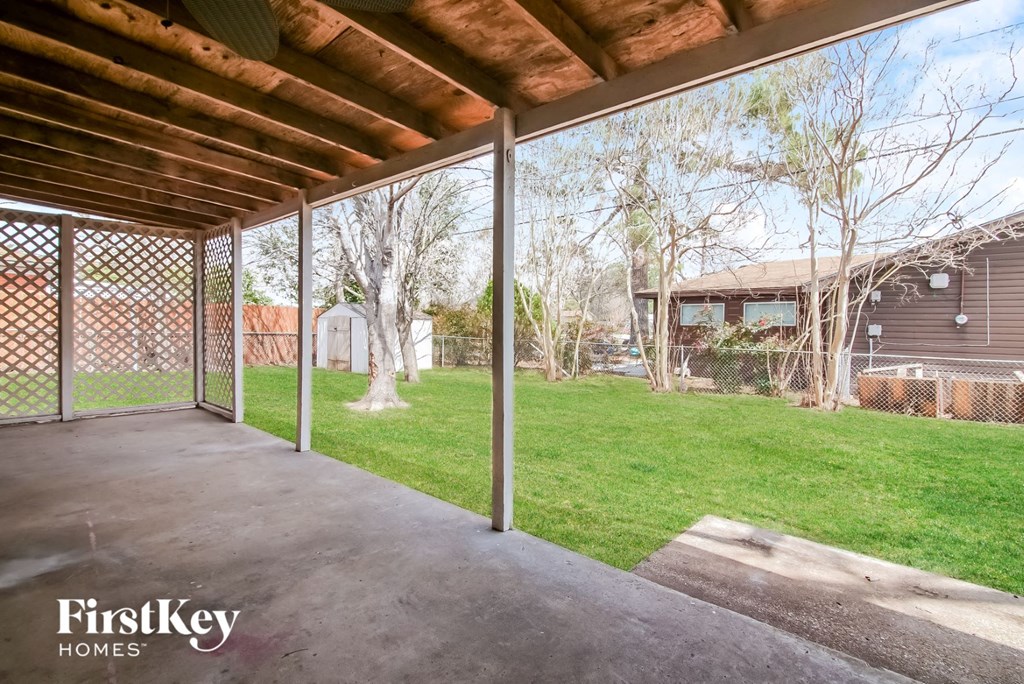 a covered patio in a backyard with a chain link fence