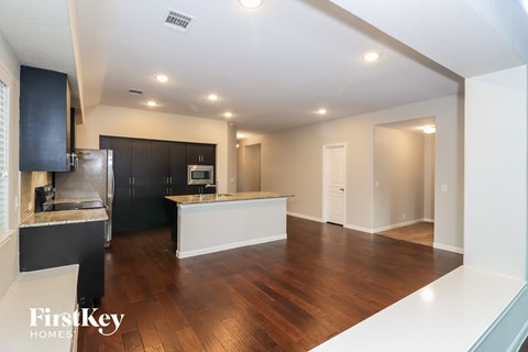 A kitchen with dark cabinets and a wooden floor.