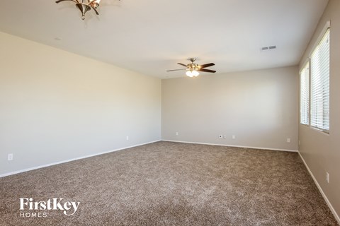 A room with a carpeted floor and a ceiling fan.