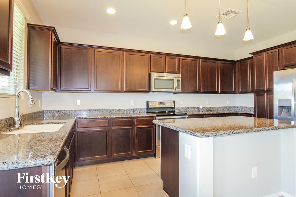 A kitchen with brown cabinets and granite countertops.