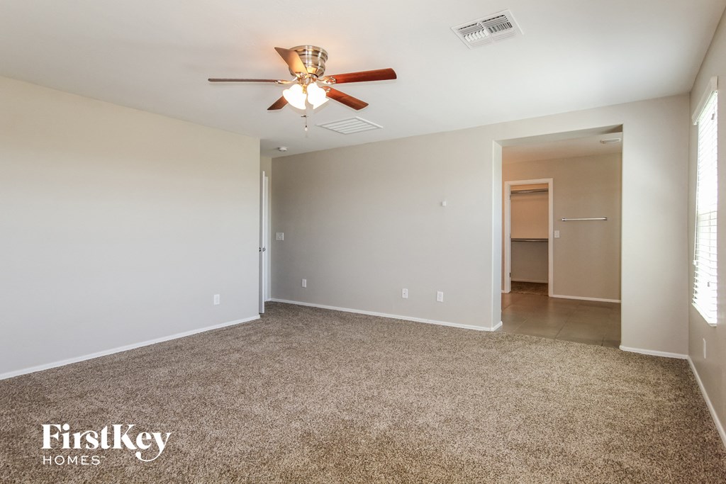 A spacious room with a ceiling fan and carpeted floor.