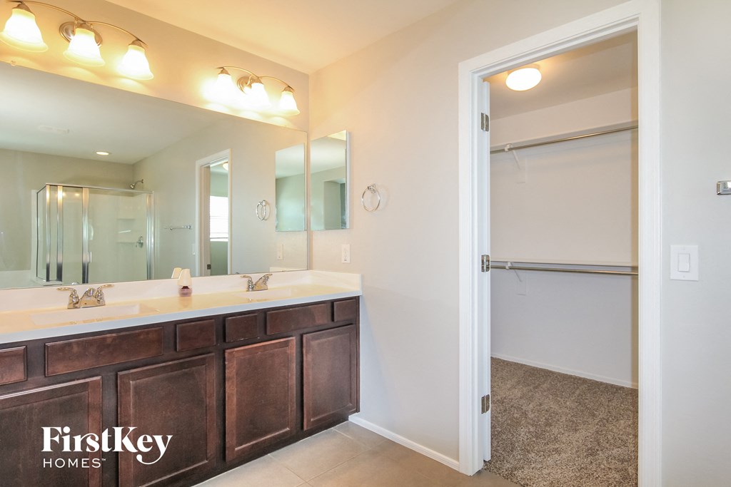 A bathroom with a double sink vanity and a mirror above it.