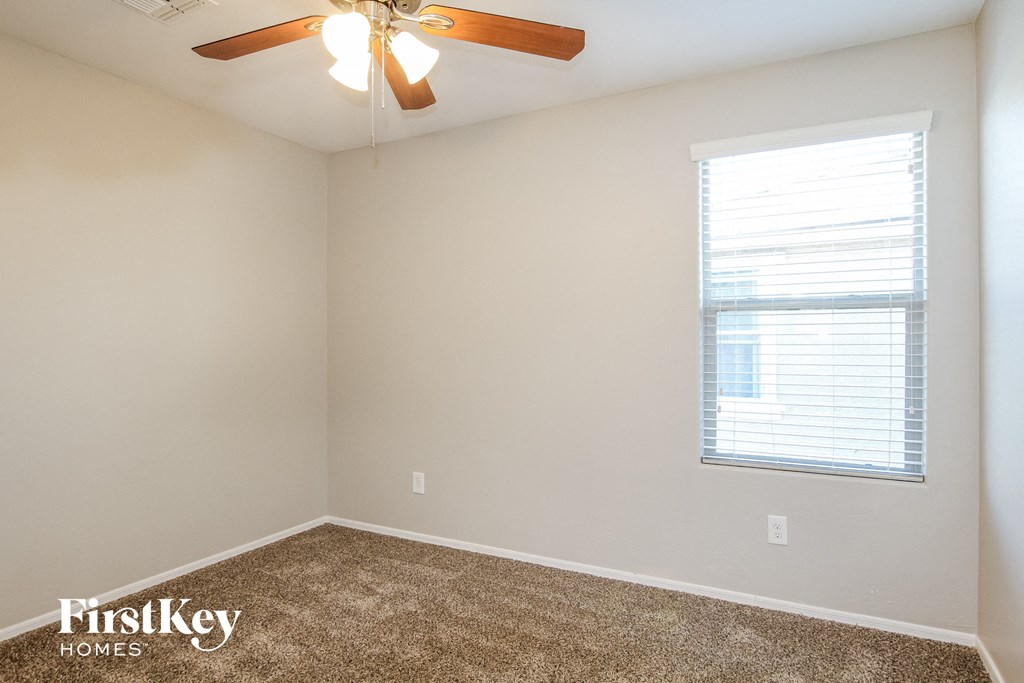 A room with a ceiling fan and a window with blinds.