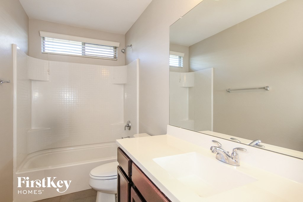 A white bathroom with a toilet, sink, and shower.