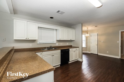 A kitchen with white cabinets and a brown counter top.
