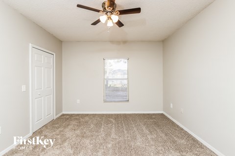 a spacious living room with carpet and a ceiling fan