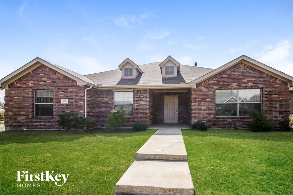 A brick house with a white door and windows is for sale.