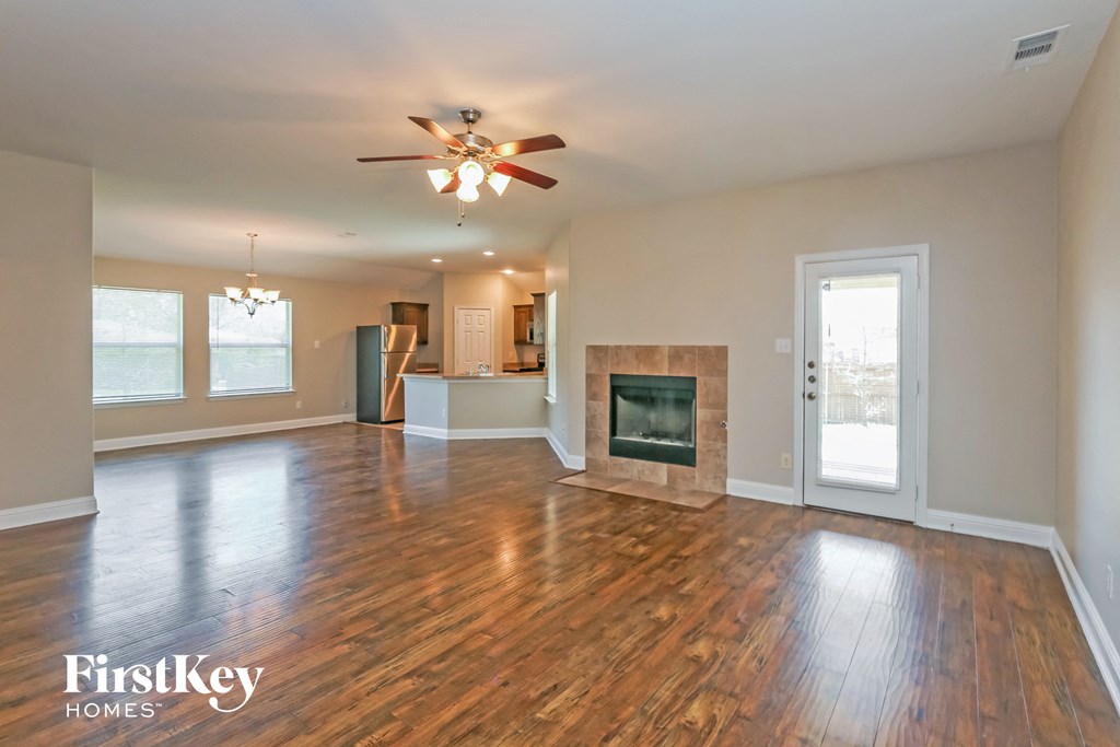A spacious living room with wood flooring and a fireplace.
