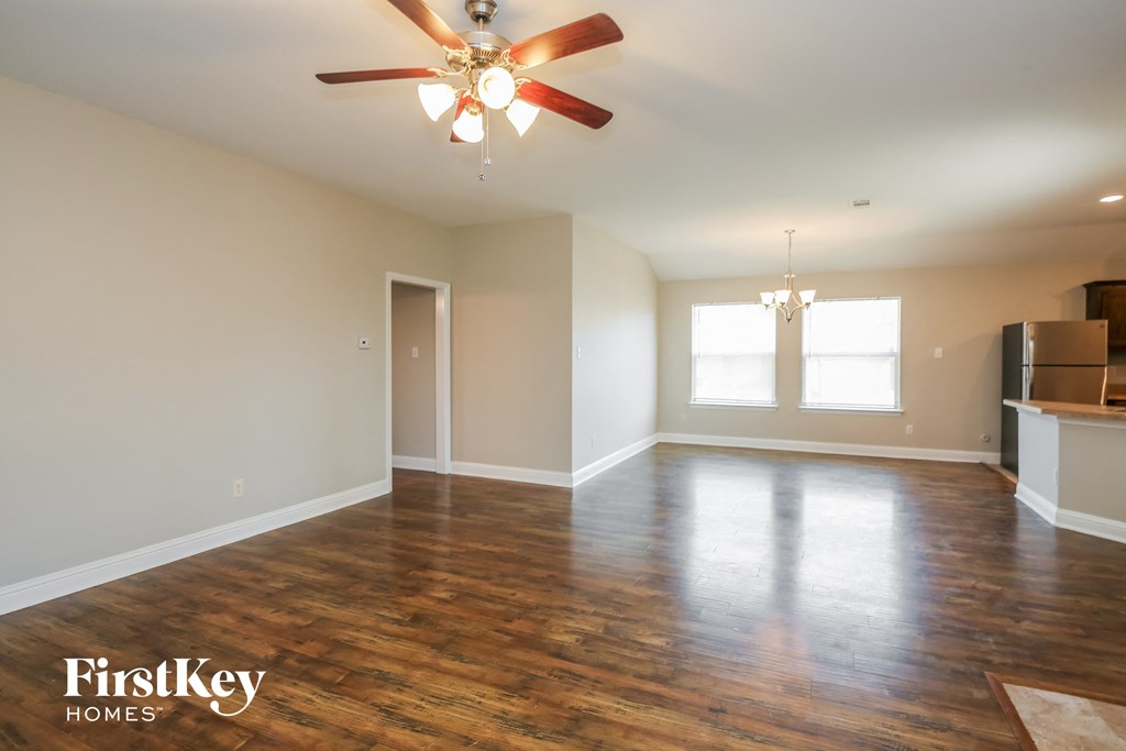 A room with a ceiling fan and wooden floors.