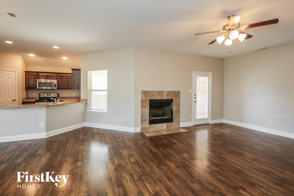 A spacious living room with wood flooring and a fireplace.