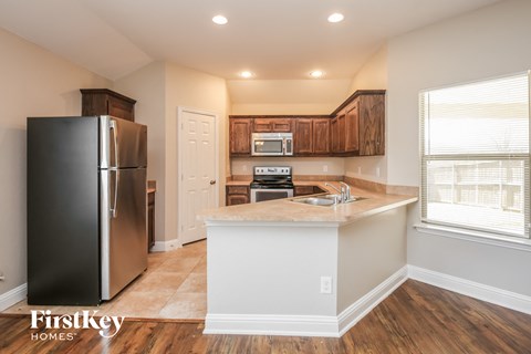 A kitchen with a black fridge and wooden cabinets.