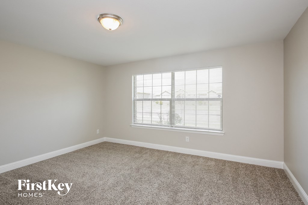 A room with a carpeted floor and a window with blinds.